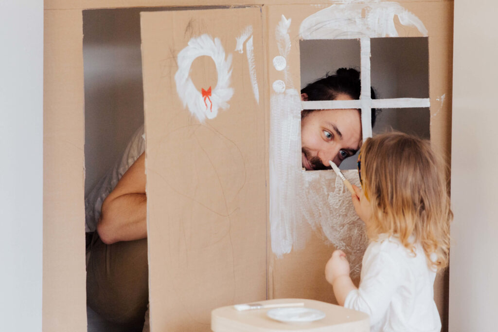 Dad with child and cardboard cubby house