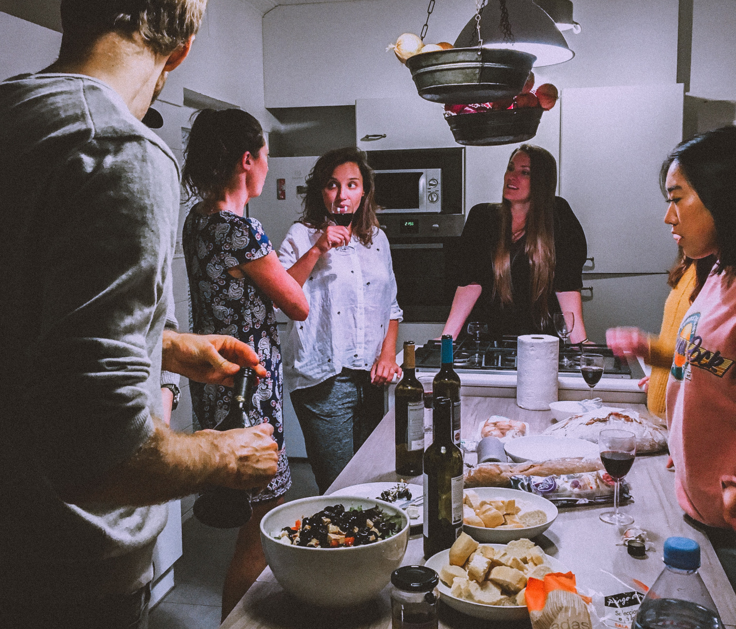 Young adults socialising in the kitchen with drinks