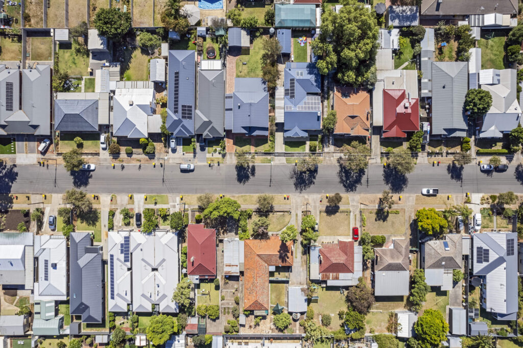 Birds eye view over Australian suburban streets, houses and backyards; the Help to Buy Scheme helps Australians to buy homes.